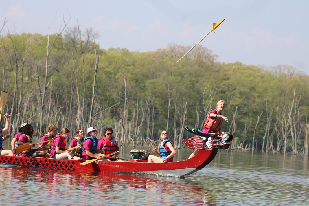 A student throws a flag into the air while riding on a red dragon boat at Big Hollow Recreation Area.