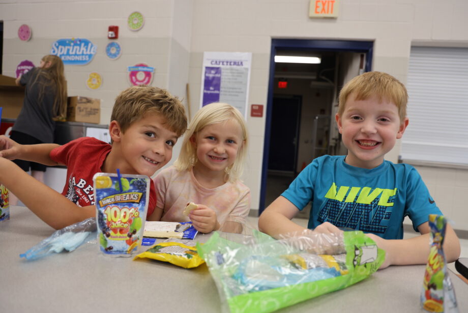 Two boys and a girl enjoy snack time in the cafeteria at Sunnyside Elementary School