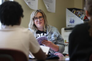 A paraeducator reads along to a book with a group of students