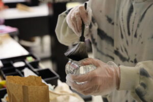 A student dusts for fingerprints on a glass