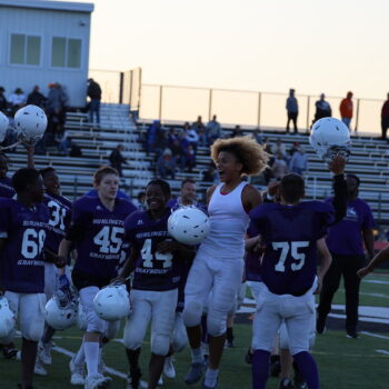 The seventh grade football team celebrates their perfect season at the close of their last game as the sun sets.