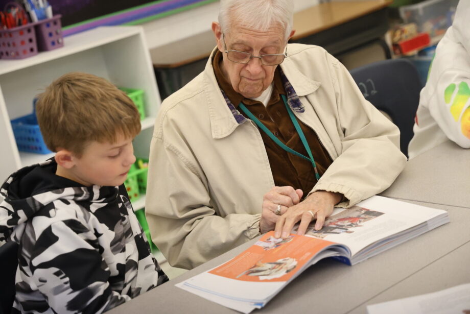 Longtime volunteer Fred Chandler and a student follow along in a textbook Thursday, Nov. 16, in Lori Johnson’s fourth grade classroom at Black Hawk Elementary School.