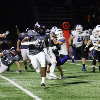 Football players play a game of football.