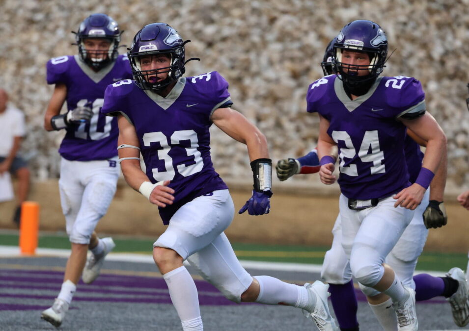 Football players run along the football field at Bracewell Stadium