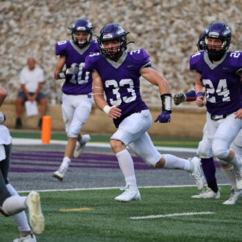 Football players run on the field during a football game.