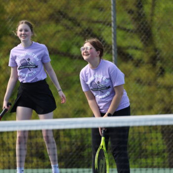 Members of the JV girls tennis team laugh while volleying ahead of a match.