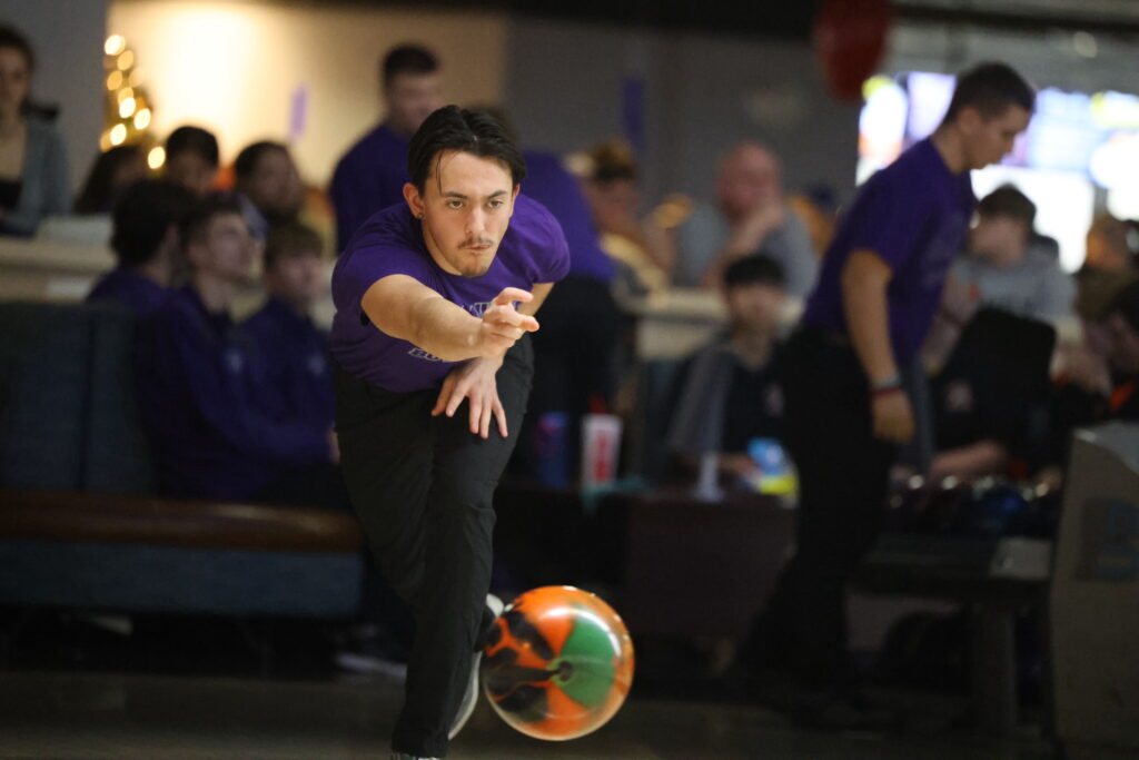 A member of the boys bowling team hurls a ball toward pins during a bowling match.