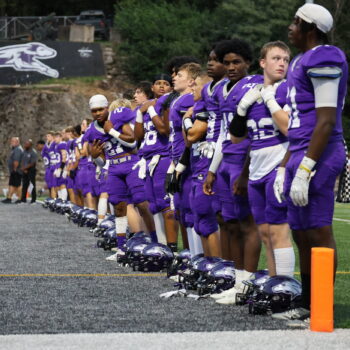 Football players stand in line for the National Anthem.