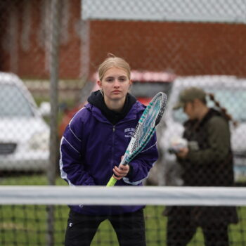 A member of the girls tennis team stands at the ready as her opponent prepares to serve the ball.