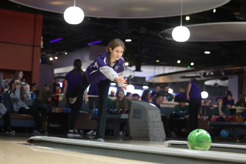 A member of the girls bowling team rolls a ball down the lane during a bowling match