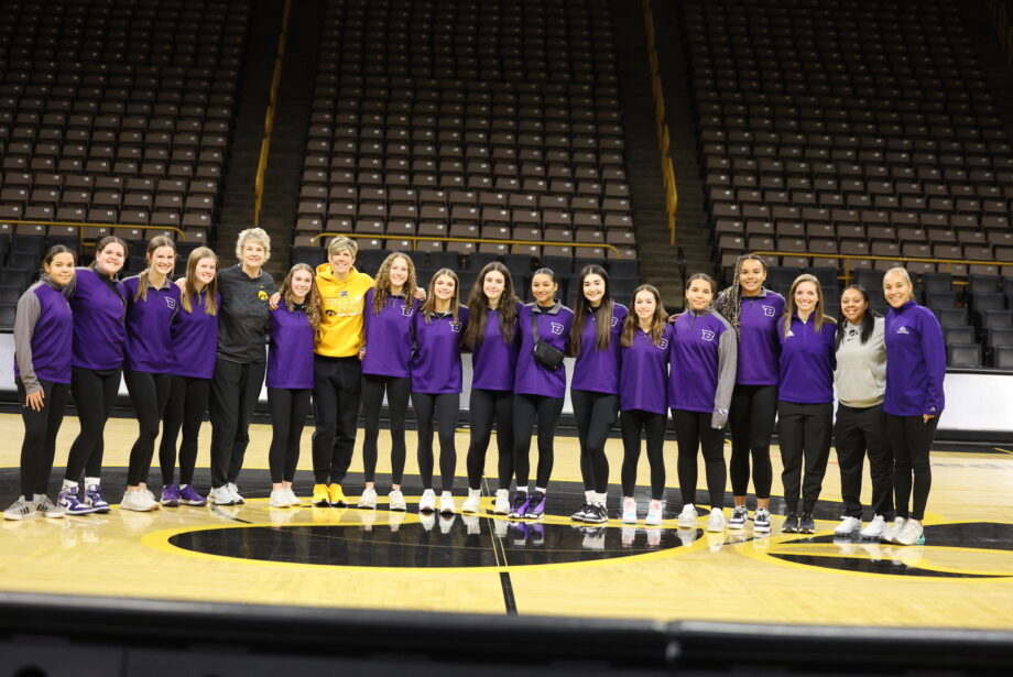 The Burlington High School girls basketball team, BHS head coach Adriana Mafra and assistant coach Amanda Kalina pose for a photo alongside Iowa head basketball coach Lisa Bluder and associate head coach Jan Jensen Sunday, Dec. 31, at Carver-Hawkeye Arena in Iowa City.