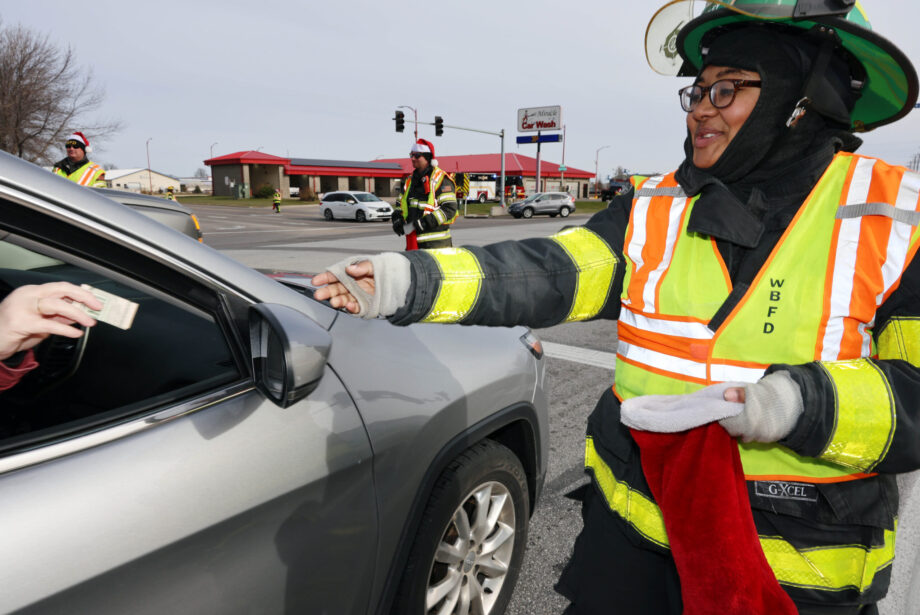 Burlington High School senior Amari Bailey collects donations Friday, Nov. 24, as members of the West Burlington Fire Department fill Christmas stockings while raising money for Toys for Tots near the intersection of Agency and Broadway. Amari officially joined the West Burlington Fire Department in December.