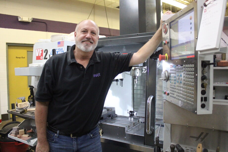 Tom Buckman stands next to a CNC machine in his classroom. Buckman has retired after a more than 30-year teaching career that began in Chicago.