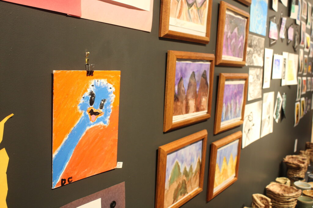 Student artwork hangs on a wall in a gallery