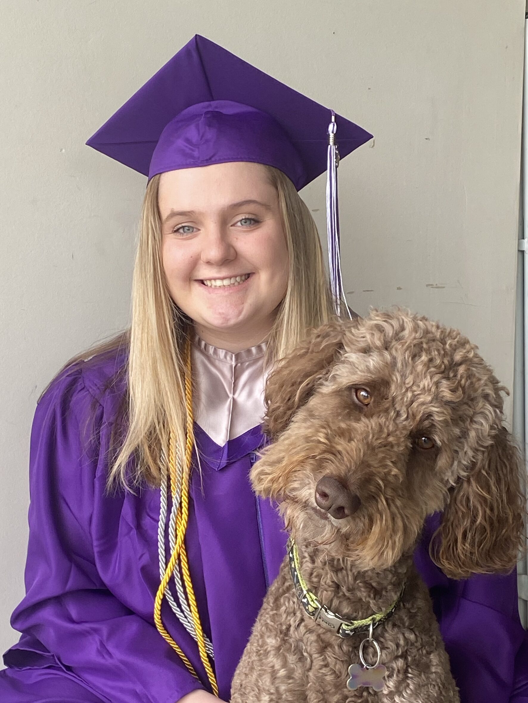 Taylor Kesterke poses for a photo in cap and gown with her dog.