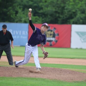 A pitcher throws a pitch from the pitcher's mound during a baseball game.