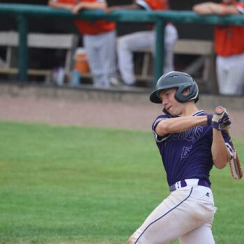 A baseball player swings a bat during a baseball game.