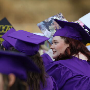 A graduating senior turns her head toward a classmate while waiting for the 2024 commencement ceremony to begin.