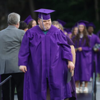 A graduate smiles while making his way back to his seat after receiving his diploma during the 2024 commencement ceremony at Bracewell Stadium.