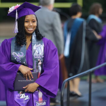 A graduate proudly displays her diploma after walking across the stage at the 2024 Commencement Ceremony at Bracewell Stadium.