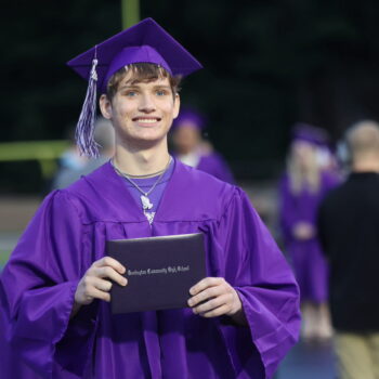 A graduate proudly displays his diploma after walking across the stage at the 2024 Commencement Ceremony at Bracewell Stadium.