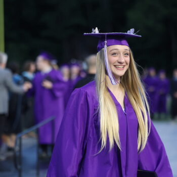 A graduate smiles while returning to her seat after accepting her diplomat during the 2024 Commencement Ceremony at Bracewell Stadium.