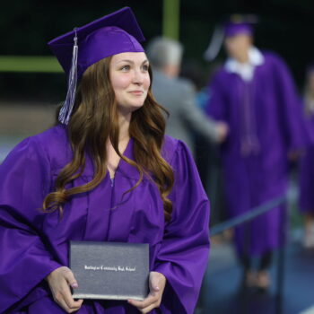 A graduate proudly displays her diploma after walking across the stage at the 2024 Commencement Ceremony at Bracewell Stadium.