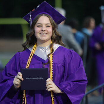 A graduate proudly displays her diploma after walking across the stage at the 2024 Commencement Ceremony at Bracewell Stadium.