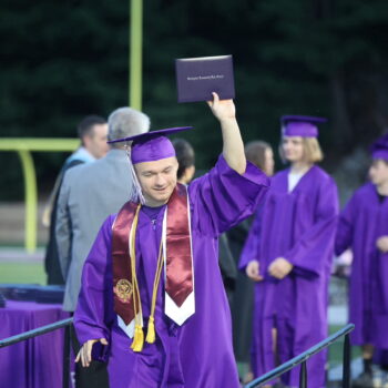 A Burlington High School graduate proudly holds up his diploma during the 2024 commencement ceremony at Bracewell Stadium.