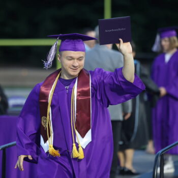 A Burlington High School graduate proudly holds up his diploma during the 2024 commencement ceremony at Bracewell Stadium.