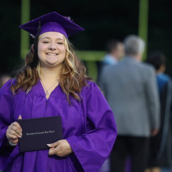 A graduate proudly displays her diploma after walking across the stage at the 2024 Commencement Ceremony at Bracewell Stadium.