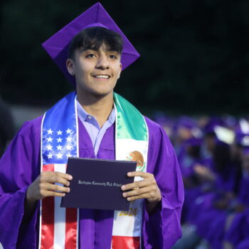 A graduate proudly displays his diploma after walking across the stage at the 2024 Commencement Ceremony at Bracewell Stadium.