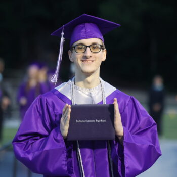 A graduate proudly displays his diploma after walking across the stage at the 2024 Commencement Ceremony at Bracewell Stadium.