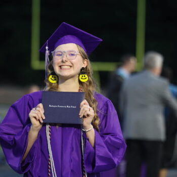 A graduate proudly displays her diploma after walking across the stage at the 2024 Commencement Ceremony at Bracewell Stadium.