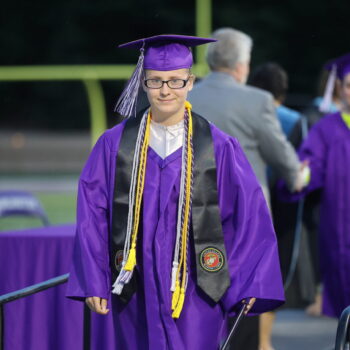 A graduate smiles after receiving her high school diploma while making her way back to her seat during the 2024 commencement ceremony at Bracewell Stadium.