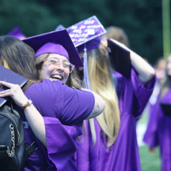 A graduate smiles while hugging a loved one following the 2024 commencement ceremony at Bracewell Stadium.