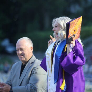 A graduate jumps up and down in excitement after directing the band one last time following the 2024 commencement ceremony at Bracewell Stadium