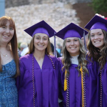 A teacher poses for a photo alongside three of her students dressed in caps and gowns following the 2024 commencement ceremony at Bracewell Stadium.