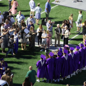 A group of graduates pose for a group photo while family members gather to take pictures following the 2024 commencement ceremony at Bracewell Stadium.