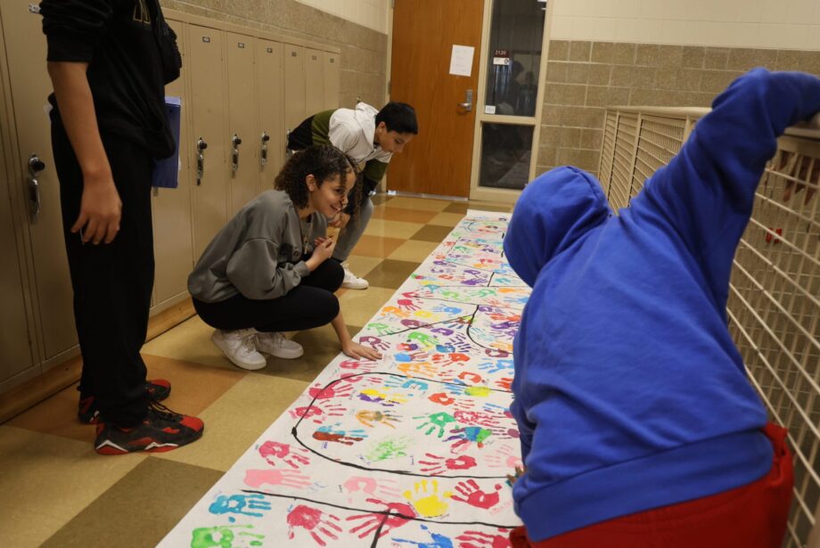 Eighth-graders decorate a GEAR UP banner with painted handprints Sept. 24, 2024, at Edward Stone Middle School.