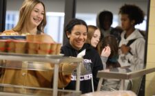 Students smile while going through the lunch line Nov. 14, 2024, at Burlington High School. Kelly Pfeifer, who is in her first year as kitchen manager, has been working to bring new items to the menu.