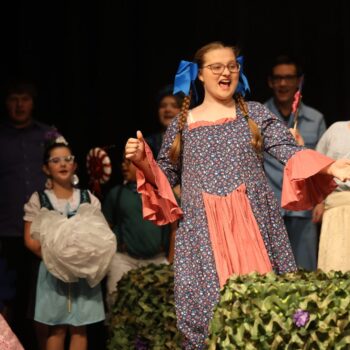 Students perform the role of munchkins on stage during a high school musical production of 