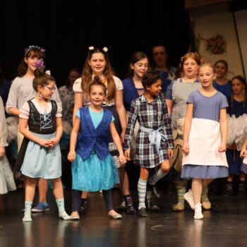 Munchkins in the Lullaby League perform on stage during a school musical production of 