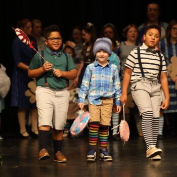 Three munchkins making up the Lollipop Guild perform on stage during the high school musical production of 