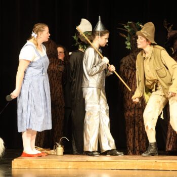 Dorothy and the Scarecrow stand on either side of a rusted-in-place Tinman during a high school production of 