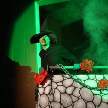 The Wicked Witch of the West sneers while leaning over a balcony during the high school musical production of 