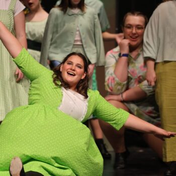 Oz residents dressed in green dance on stage during the high school musical production of 