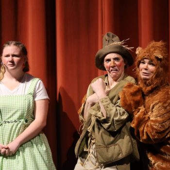 Dorothy stands alongside a scared looking Scarecrow and Lion while onstage during the high school musical production of 