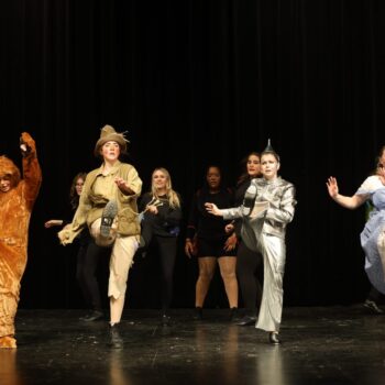 The Cowardly Lion, Scarecrow, Tin Woodsman and Dorothy dance onstage during a jitterbug scene during the high school musical production of 