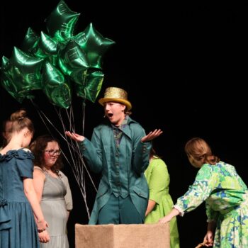 The Wizard of Oz floats away in his balloon with assistance from Oz residents during the high school musical production of 